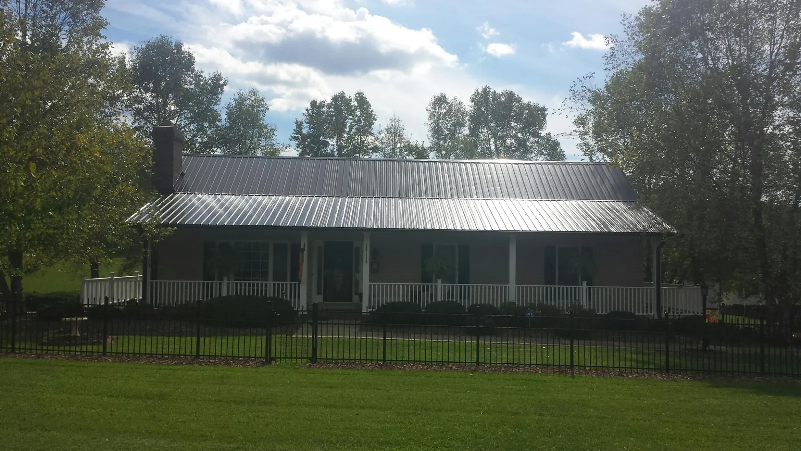 Gray metal roof on a brick ranch with a full width front porch — Gutter Guard Installation work by our crew in Rushville